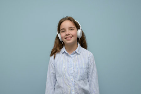 Enjoying music. Satisfied teenage girl listens to music in headphones. A teenage girl in headphones listens to songs on a headset. Positive internal stateの写真素材