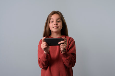 The girl looks at the smartphone in a horizontal position. Seagreen backgroundの写真素材