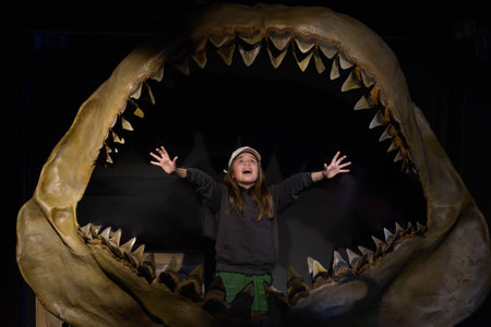 The jaw of a giant shark, a sea monster in the installation. Teenage girl is terrified
