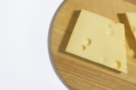 Emmental cheese on a round wooden kitchen board. Cheese with holes. Close-upの写真素材