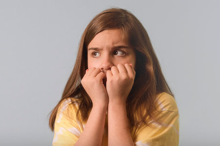 Scared child. Close up on a gray background. Teen girl in a frightened pose looks with fear.
