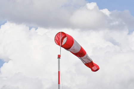 Red and white windsock, on clouds sky, windy weather forecast conceptの写真素材