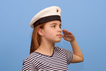 Sailor girl 10-12 years old on a blue background, a teenage girl in a sailor suit looks intently into the distance.の写真素材