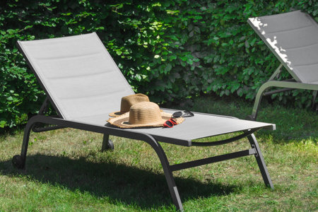 Two beach hats and sunglasses of a man and a woman left on a beach lounger. Summer still lifeの写真素材