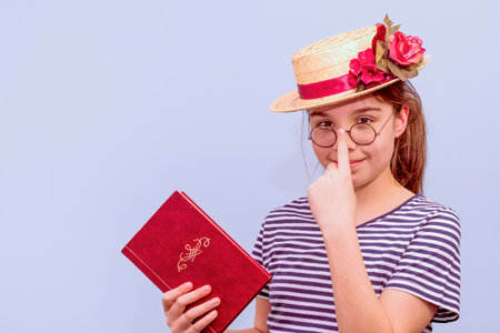 A girl in a retro fashion of past, a straw hat with flowers, glasses and a book in her hand. closeの写真素材