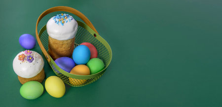 Banner with Easter basket, Easter cakes and eggs. Green background. Place for text