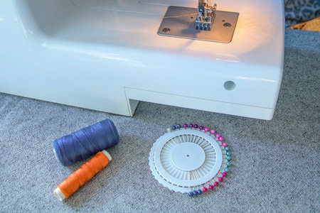 A sewing machine with a spool of thread and a needle on a table
