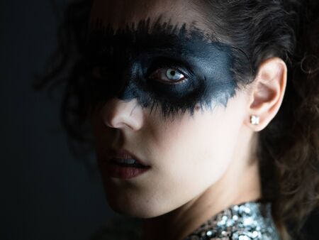 Beautiful woman black painted face and glittery jacket