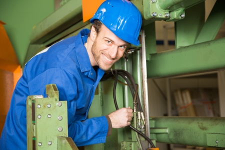 Engineer with helmet repairing and maintaining a machine