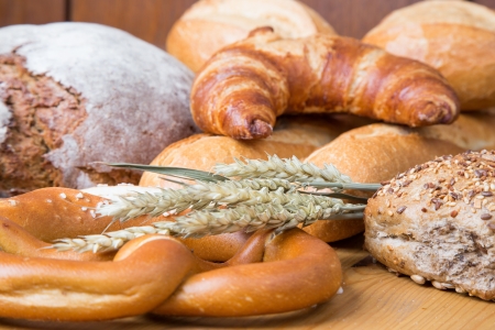 Different types of bakery products such a a loarf of bread, pretzel, whole grain bread and bunsの写真素材