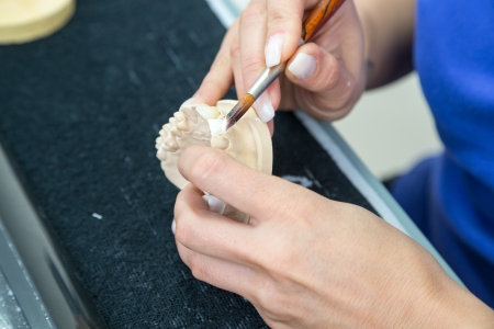 Dental technician applying ceramics to a mold