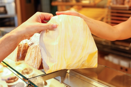 Bakery shopkeeper hands bag of bread over to customerの写真素材