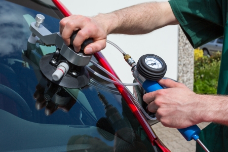 Glazier repairing windshield on a car after stone-chipping damage