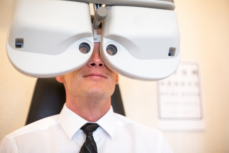 Customer of a optometrist or optician looking through phoropter to determine the right glassesの写真素材