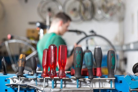 Tools in a workshop with bicycle mechanic repairing a wheel in the backgroundの写真素材