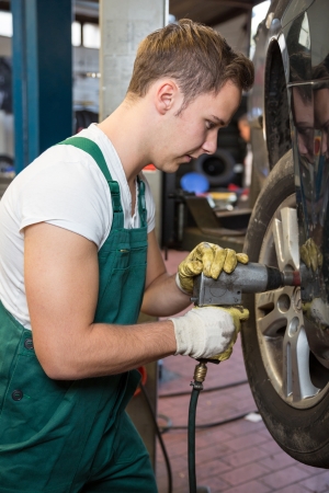 Mechanic replacing the tire or wheel on a car in garageの写真素材
