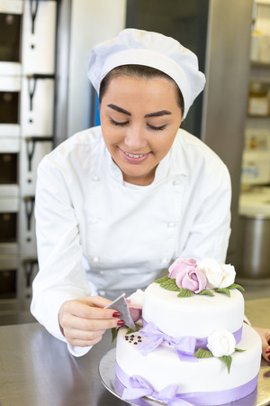 Baker or confectioner writes something on a cake with food colouringの写真素材
