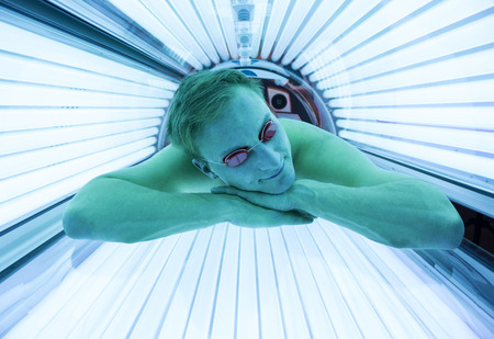 Man with sunglasses on tanning bed in solariumの写真素材