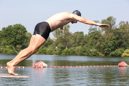 Man jumping off diving board at a public swimming poolの写真素材