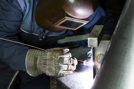 professional welder welding metal parts in steel construction company