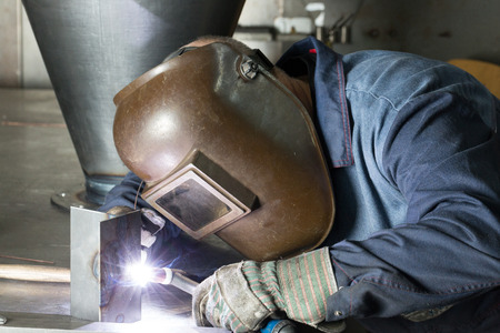 professional welder welding metal parts in steel construction company