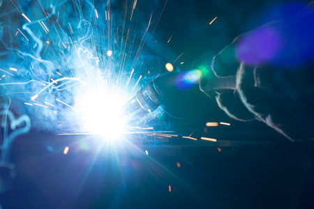 Closeup of welding metal with arc, sparks and torch