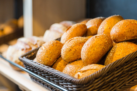 Bread and buns in baskets on shelf in bakery or baker's shop