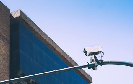 Security camera on blue sky background and glass building