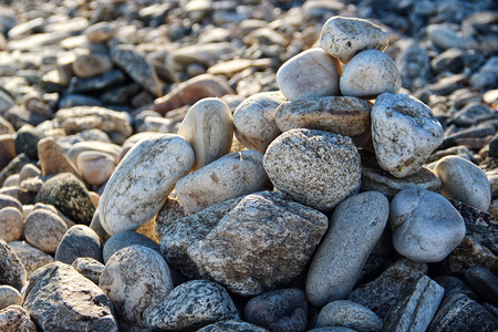 Pebble stones stacked by a heap on the beach in the sun as a texture or background