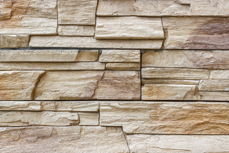 Decorative brick wall as background or texture. Artificial facing torn stone in brown tones in a...