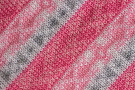 knitting fabric with a pattern tied with pink, grey and white yarn, handmade. Background, texture