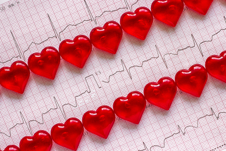 Two rows of red hearts on the background of the electrocardiogram (ECG). Heart rate.