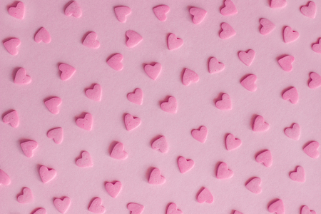 Pattern. Pink confectionery sprinkles in form of hearts on pink background, textureの写真素材