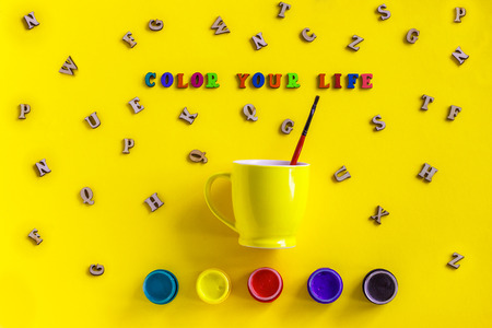 Lettering Color your life from colorful letters, gouache, yellow coffee cup with paintbrush, scattered wooden letters. Still life on yellow background  Flat lay Top view,  greeting card. Concept - Paint your life. Itâs up to youの写真素材