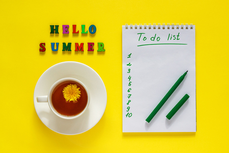 Lettering Hello summer, Ñup of tea with dandelion,  To Do List, pen. Still life on yellow background. Concept  to-do list for summer holidays or vacationの写真素材