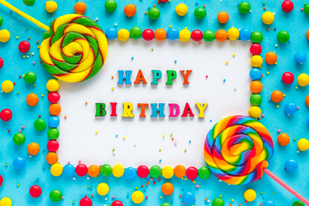 Text HAPPY BIRTHDAY, colored letters, greeting card, candy and lollipops, blue background, Top view, Flat Layの写真素材