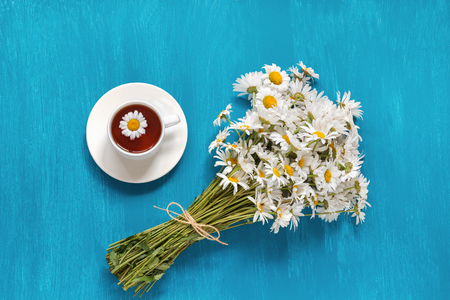 Bouquet Flowers field Chamomiles Cup of Herbal Tea on blue wooden background, Rustic Vintage Style, Concept Good morning  Summer Teatime Tea party Flat Layの写真素材
