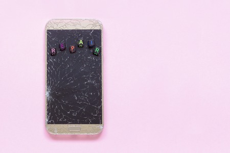 Broken cracks cell mobile phone and text repair on pink background Concept Copy Space Flat Lay