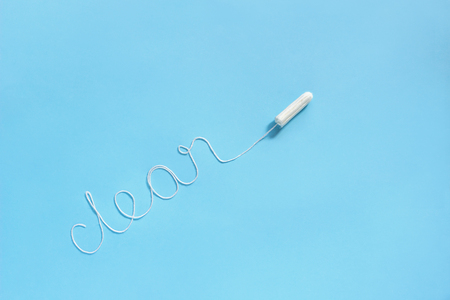 Word CLEAN from white thread hygienic female tampon is located diagonally on blue background. Concept hygiene and health women and adolescents during menstrual cycle. Flat Lay, copy spaceの写真素材