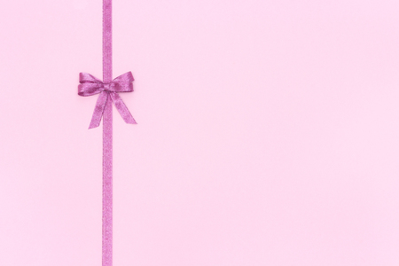 Decorative shiny ribbon with bow on pastel pink background with copy space for text, Top view, Layoutの写真素材