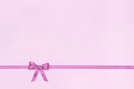 Decorative shiny ribbon with bow on pastel pink background with copy space for text, Top view, Layoutの写真素材