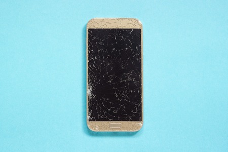 Broken cracks cell mobile phone on blue background Concept Copy Space Top viewの写真素材