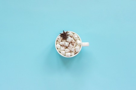 Winter composition. Cup of cocoa with marshmallows and anise star on blue background. Top view Flat lay Greeting card Copy spaceの写真素材