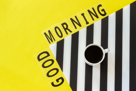 Text Good morning and Cup of coffee on stylish black and white napkin on yellow background. Minimal style. Concept good morning or day. Flat lay Top view Copy space.の写真素材