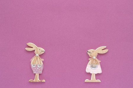 pair of wooden easter bunnies on purple paper background. Concept Easter or Valentine's day Copy space Template for lettering, text or your design Creative Top View.の写真素材