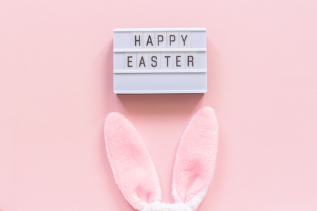 Lightbox text Happy Easter and bunny ears on pink paper background. Concept Easter minimal style Creative top-down composition Flat lay Greeting card.の写真素材