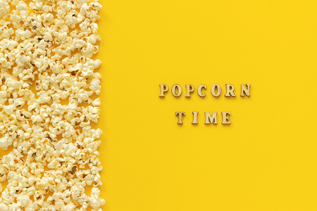 Scattered popcorn border left edge and popcorn time on yellow paper background. Top view Copy space Template for text or your design.の写真素材