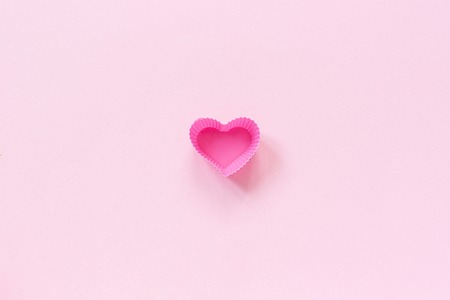 Silicone heart shaped mold dish for baking cupcakes on pink paper background. Template for lettering, text or your design Top view, copy space Minimal style.の写真素材