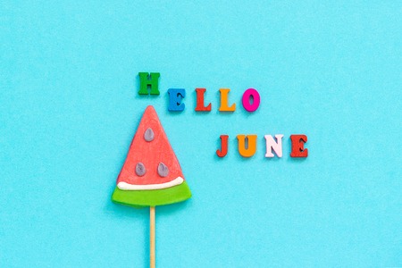 Hello June colorful text and watermelon lollipops on stick on blue paper background. Concept vacation or holidays Creative Top view Template Greeting card, postcard.の写真素材