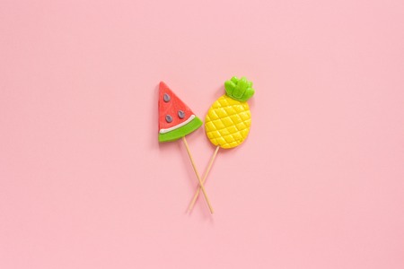 Pineapple and watermelon lollipops on stick on pink background. Concept Summer vacation or holidays...